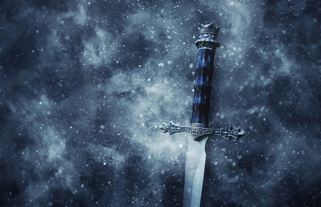 神秘而神奇的银剑照片覆盖哥特式雪黑色背景。 中世纪时期概念