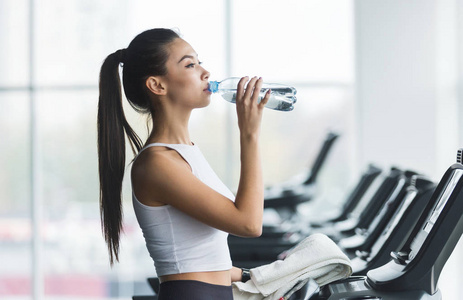 在跑步机上锻炼后喝水的妇女照片