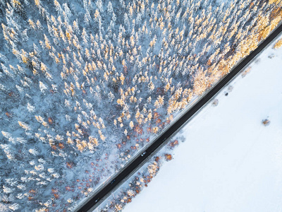 森林冬季道路上汽车的鸟瞰图。 冬季景观乡村。 空中摄影雪林与一辆汽车在路上。 用无人机从上面捕获。 空中照片。 汽车在运动