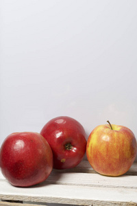 成熟多汁的苹果。他们躺在木箱上。在白色背景上。