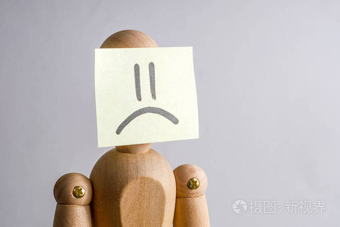 不快乐的人的概念脸木制人体模型脸上贴着一张贴纸带有悲伤的形象