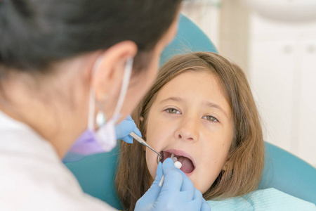 s . little girl sitting in a chair near a dentist after de