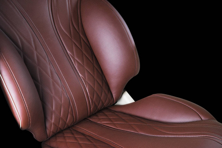 豪华现代汽车的棕色皮革内饰。 穿孔皮革舒适的红色座椅与缝纫隔离在黑色背景。 现代汽车内饰细节。 汽车细节