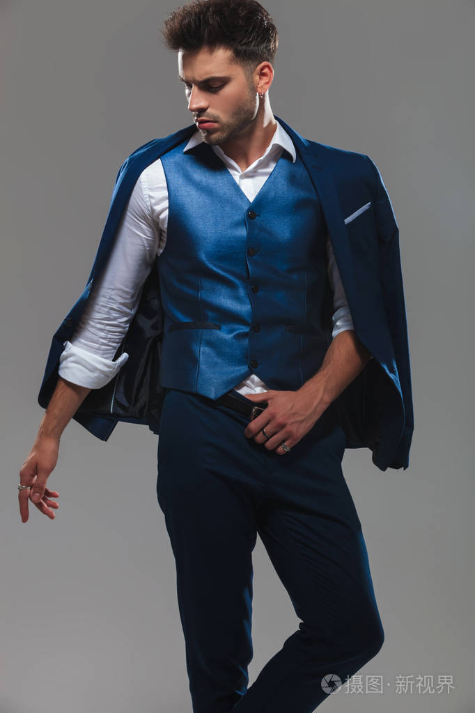 有吸引力的绅士的肖像在俯视侧面站在浅灰色背景上