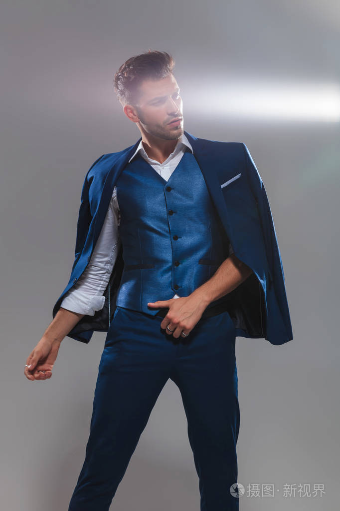 绅士的肖像肩上穿着蓝色西装站在浅灰色的背景上俯视着