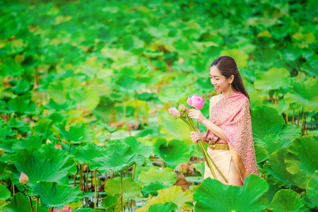 穿着泰国衣服的女人向僧侣们收集莲花船。