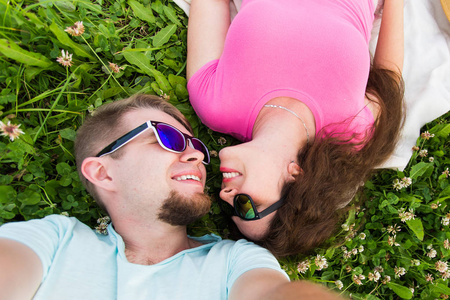 爱, 浪漫和温柔的概念关闭一对年轻而有吸引力的夫妇躺在绿草上的自拍, 顶视图