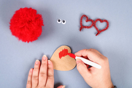 红色手工DIY怪物POM从纱线绳茎形状的心脏。 礼物的想法，情人节的爱的概念，2月14日。 儿童工艺品的过程。 上面的风景。
