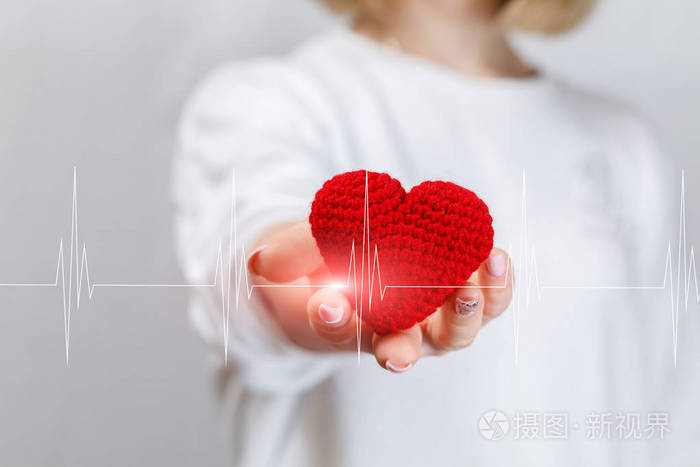 一个年轻的女人手里拿着一颗针织的小心脏,心脏线穿过.