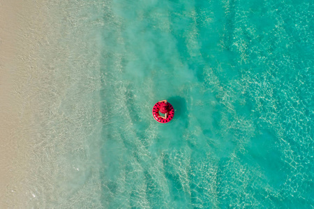 鸟瞰苗条的女人在塞舌尔透明的绿松石海中游泳圈甜甜圈。 夏天海景与女孩美丽的波浪，五颜六色的水。 无人驾驶飞机的俯视图