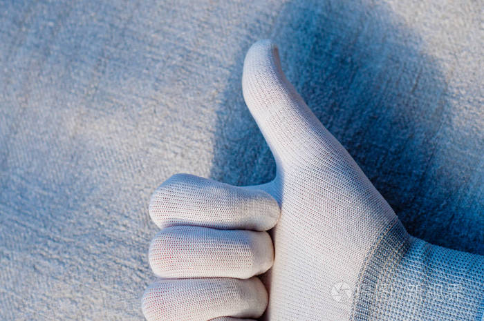 白色标牌中的一只手在织物结构的背景上显示了质量标记