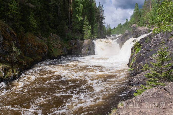 流水在岩石之间奔腾. 白色泡沫和喷雾在阳光下闪闪发光.