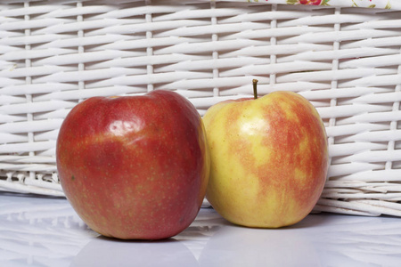 桌子上的苹果。 在白色柳条篮子旁边。