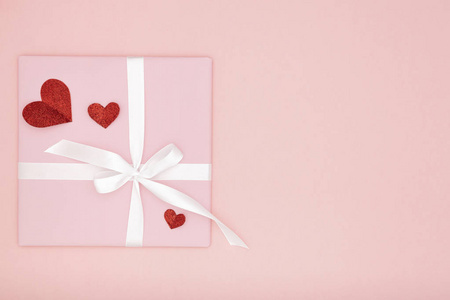 情人节理念构图 粉红色礼品盒, 白色丝带和小红心纸珊瑚背景。顶部视图。爱天概念平放置