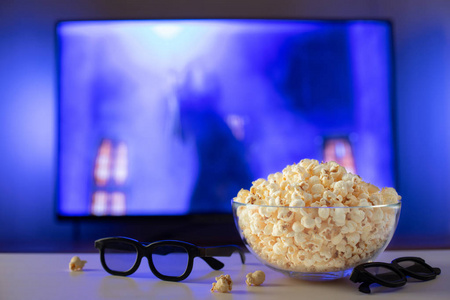 电视的背景是一碗爆米花3d 眼镜和遥控器。晚上在家里看电影或电视系列