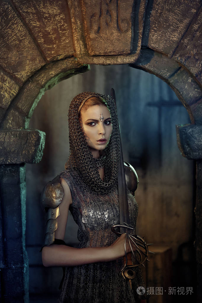 一个穿着剑和盔甲的美丽的战士女孩.穿链裙的模特和神秘的马甲的背心.