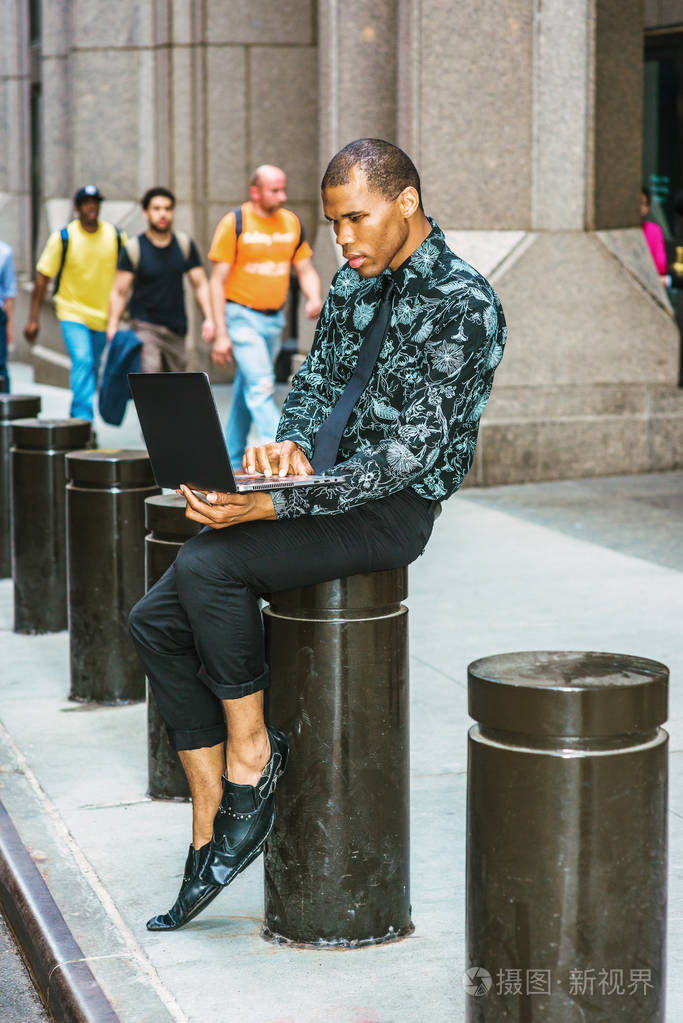 美国黑人商人头上戴着伤疤在纽约街头的笔记本电脑上工作,他的理念是