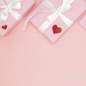 装饰情人节在桌面查看背景。扁平的形状组成的红色形状的心脏和粉红色的礼品盒与白色丝带珊瑚纸背景模拟您的设计。爱日概念