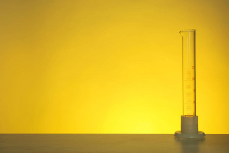空的刻度圆筒在桌子上的颜色背景。 化学实验室玻璃制品