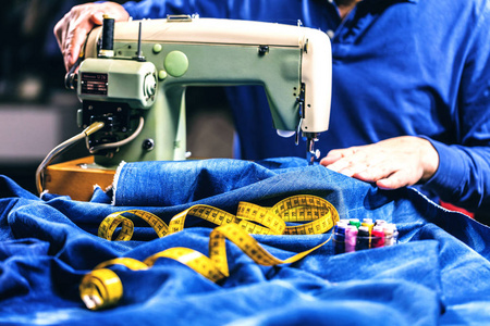 用缝纫机修理牛仔裤. 一条牛仔裤手工制作服装工业概念照片