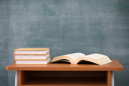 学校课本和黑板课桌上的课本和木制背景教育概念的黑板照片