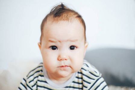 黑眼睛黑头发哭闹的不快乐的严肃女婴画像。哈萨克女孩
