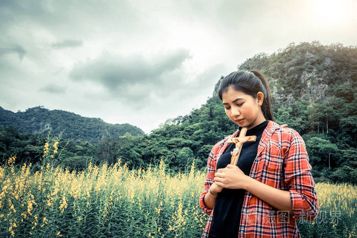 年轻漂亮的女人在大自然的背景下祈祷希望和信仰的概念
