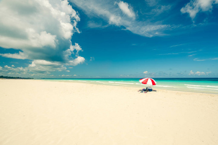 美丽的瓦拉迪罗海滩在阳光明媚的日子里，细白的沙子绿松石和绿色的加勒比海在右边，一个红色的阳伞。概念影印空间复古风格。