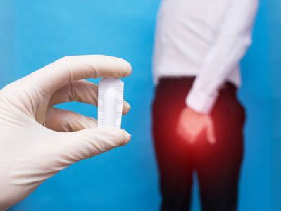 医生拿着直肠和痔疮的治疗栓剂, 男子紧紧抓住痔疮和肛裂问题的照片