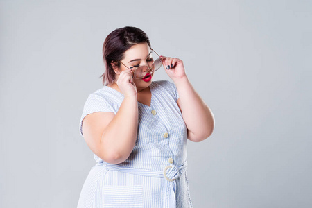 肥胖模特加上太阳镜的尺寸时尚模特. 灰色背景肥胖女性超重女性照片