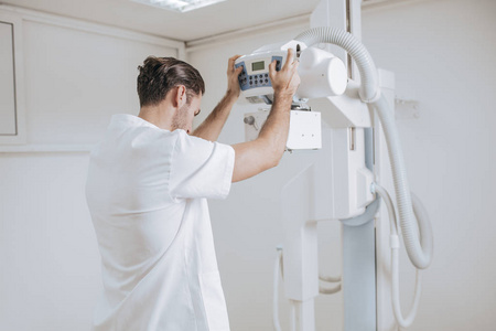 一名年轻的医疗技术人员在诊所操作X射线机器的后拍。