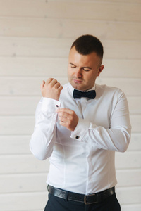 帅气的新郎穿着白衬衫和蓝色的领结。新郎在他的婚礼上穿上了衣服