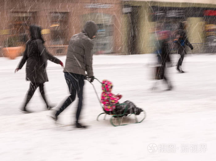 父亲和女儿坐雪橇在运动模糊。 离焦图像