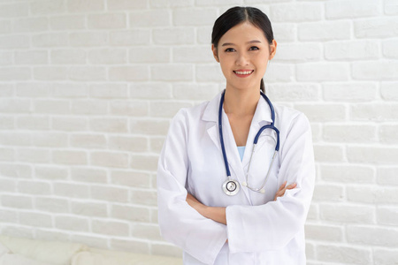 微笑的美丽的亚洲女医生的特写肖像,双臂交叉站立.