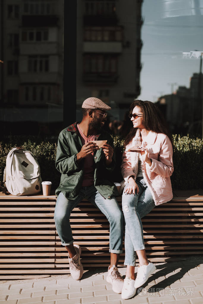 年轻心爱的夫妇坐在木栏杆上