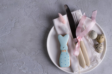 复活节节日餐桌设置复活节兔子饼干鹌鹑蛋。 在灰色的混凝土背景上。