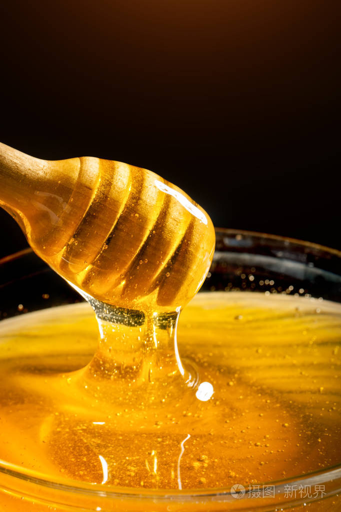 金色的蜂蜜从勺子里流下来。健康食品理念。健康饮食。饮食。选择性对焦
