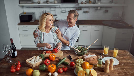 高级夫妇正在厨房做饭。 美丽的女人和英俊的男人在家里在一起。 健康的生活方式概念。