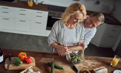 高级夫妇正在厨房做饭。 美丽的女人和英俊的男人在家里在一起。 健康的生活方式概念。