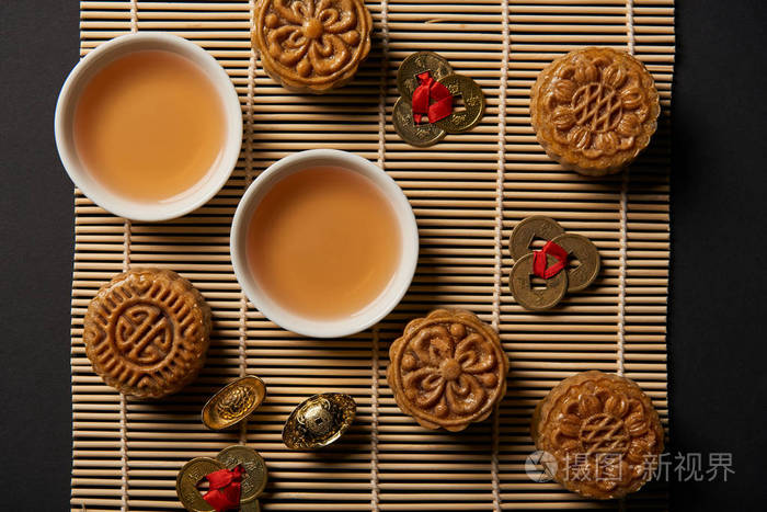 月饼风水币和竹桌垫上有杯子的茶壶的顶部景观