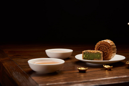 传统的中国月饼杯茶和金锭分离在黑色