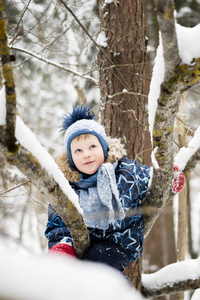 快乐的童年冬天在雪林里爬树的快乐的小男孩