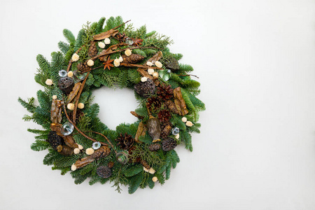 美丽的手工制作的圣诞花环被隔离在白色背景的绿色云杉枝上，上面装饰着松果和其他装饰品