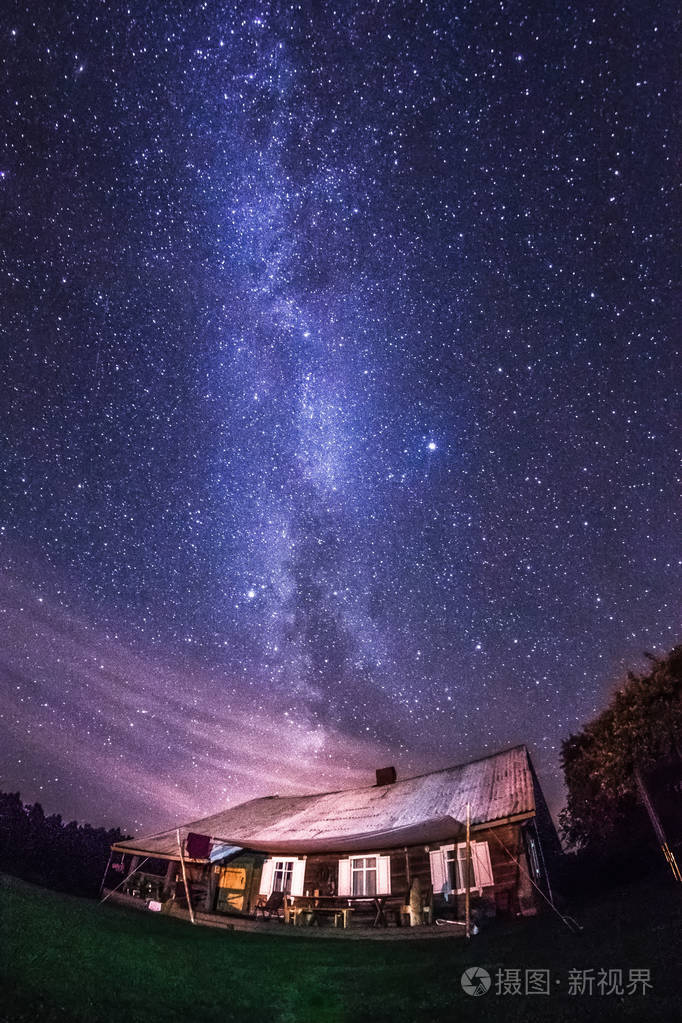 夜景与五颜六色的银河明星在树木和城市外的乡村家园夏天的星空和家在