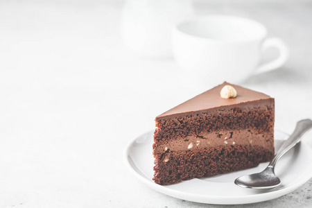 一块巧克力蛋糕在白色盘子白色背景复制空间。 纯素甜点植物为基础的食品概念。