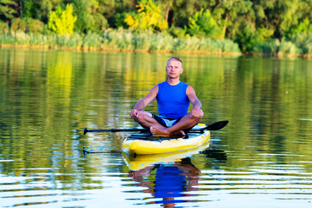 人在大河上放松和冥想，享受生活。 站起来划桨登机，令人敬畏的积极户外娱乐。