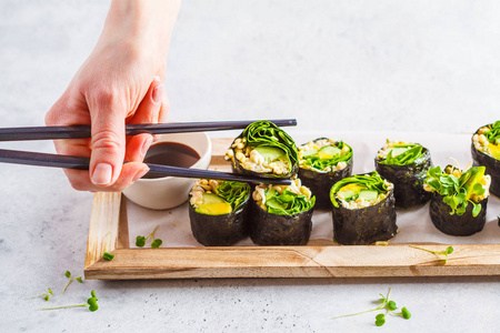 素食绿色寿司卷与鳄梨芽黄瓜和诺里在木板灰色背景。