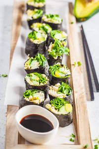 素食绿色寿司卷与鳄梨芽黄瓜和诺里在木板灰色背景。