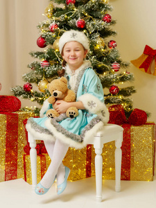 小女孩在雪少女服装与泰迪熊附近日