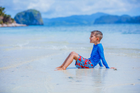 在热带海滩游泳的可爱的小男孩